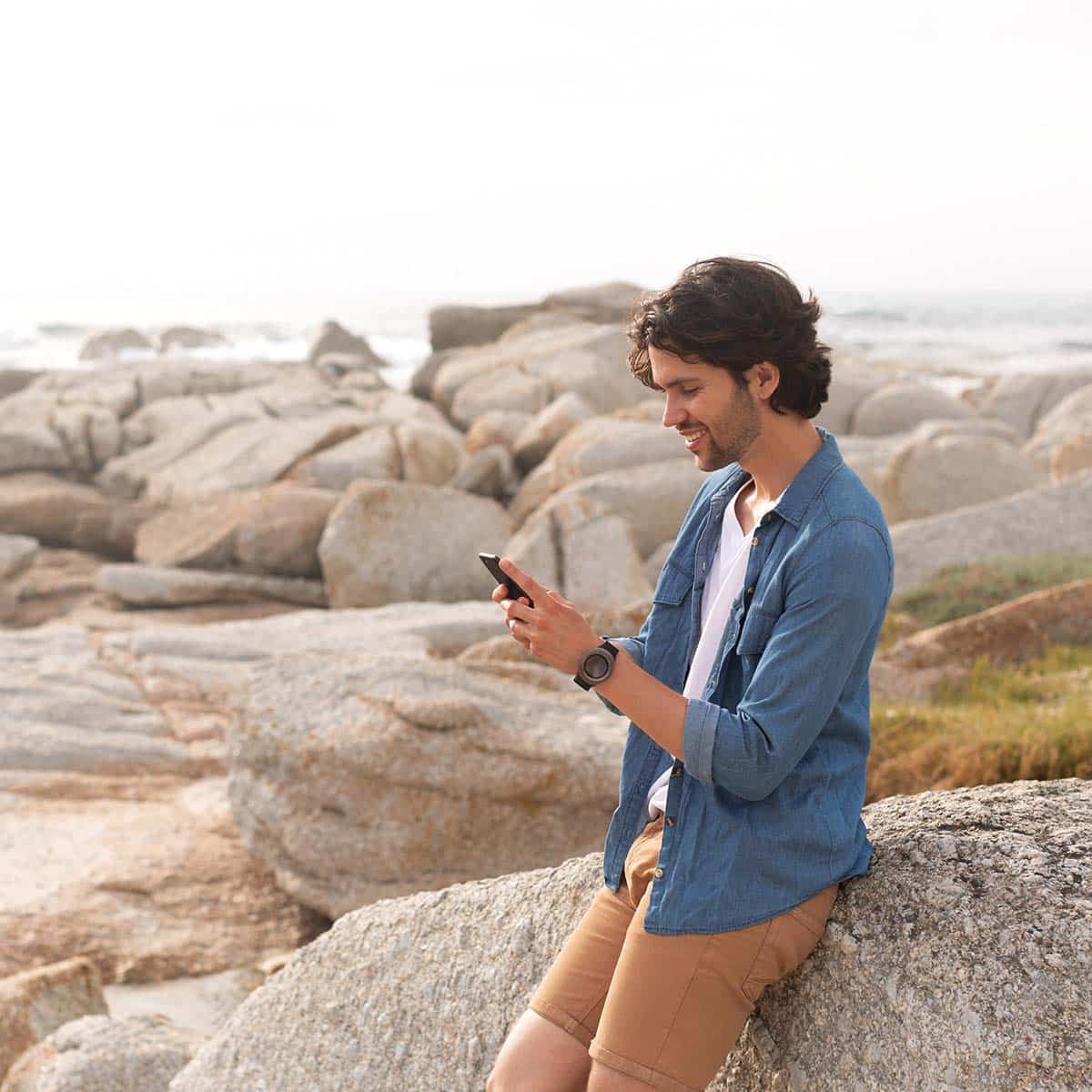 Student mit Smartphone am Strand